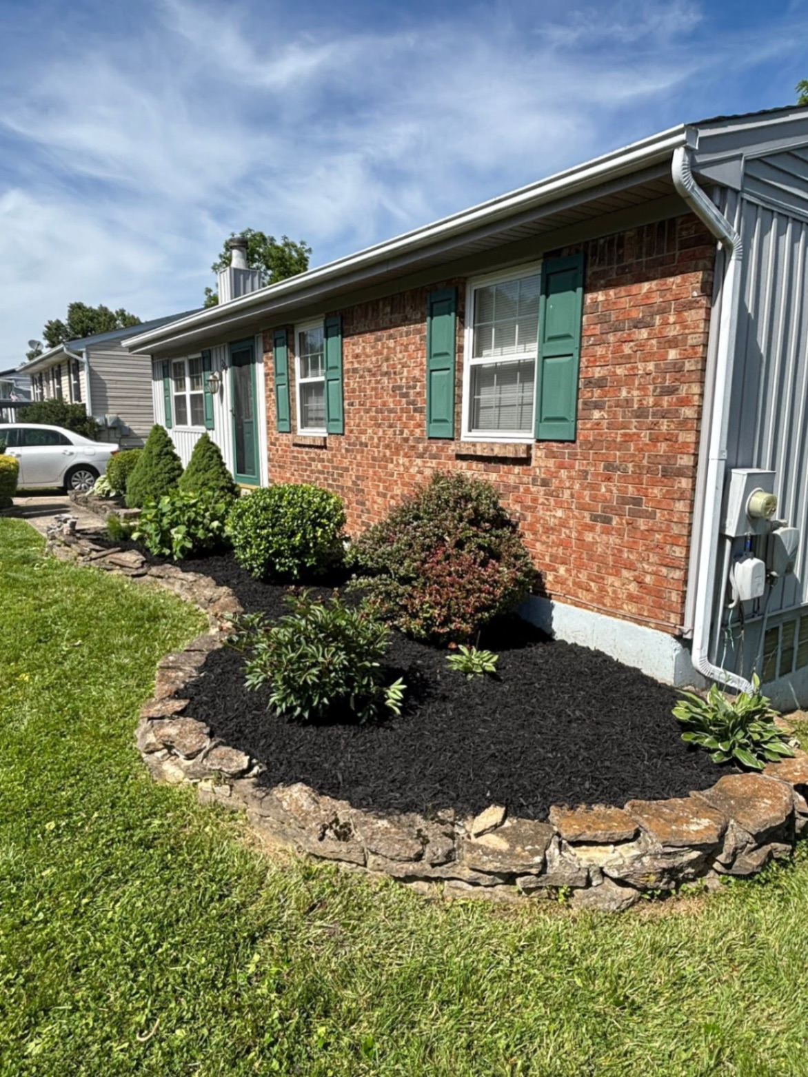Fresh black mulch bed with trimmed shrubs along a brick home foundation