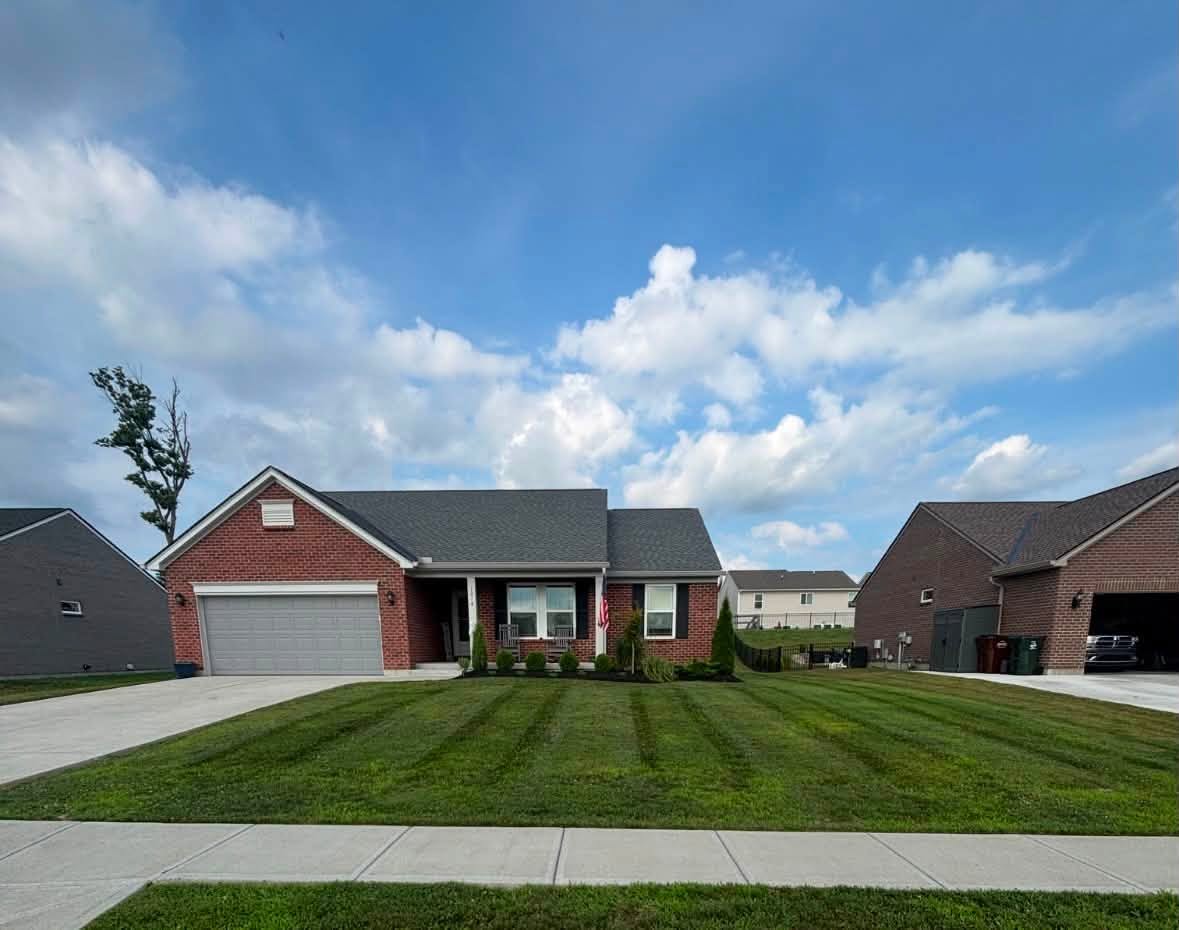 Brick ranch home with a wide striped front lawn under a bright sky