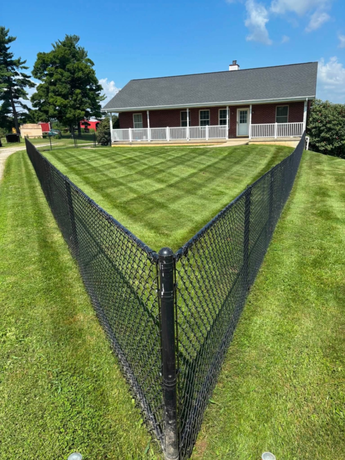 Fenced backyard with checkerboard mowing pattern in front of a ranch home